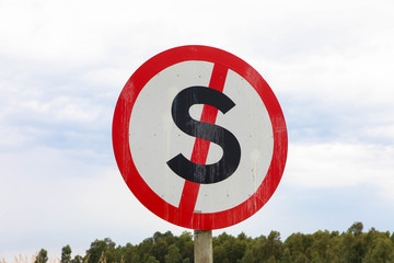 Dont stop traffic sign symbol. Red metal red s cross with circle with sky and trees background
