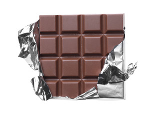 Delicious milk chocolate bar wrapped in foil isolated on white