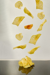 Naklejka premium Potato chips falling white background and black reflection