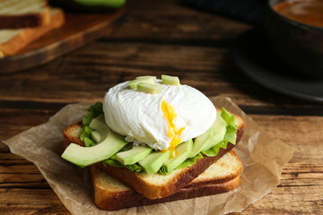 Delicious poached egg sandwich served on wooden table