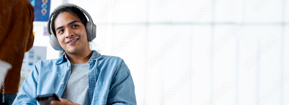 Poster asian man designer listening music with headphone take a break from meeting in modern office.digital