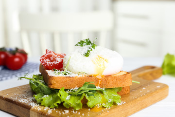 Delicious poached egg sandwich served on wooden board, closeup
