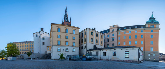 Fototapeta premium Court houses on the island Riddarholmen with the steeple of the church Riddarholmskyrkan at sunrise a spring day in Stockholm.