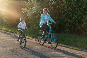 Mother and son riding bikes in the spring sunlight on a country road.
