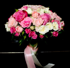 a beautiful bouquet of the bride of small pink and white roses stands on a black background.