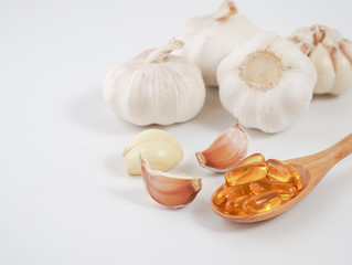 Capsule garlic oil in wooden spoon with fresh garlic, the benefit of garlic is prevent the occurrence of heart disease