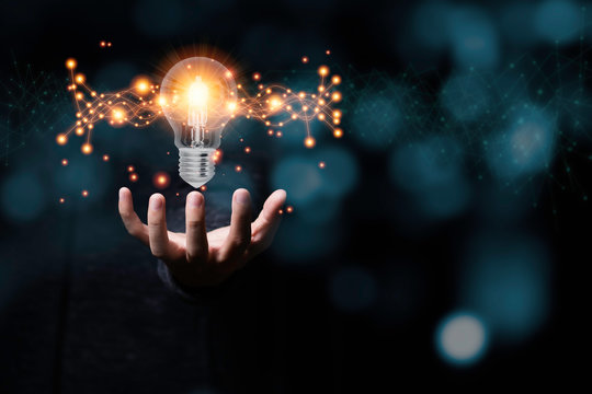 Hand holding light bulb glowing with orange light line and ray. Creative and new business idea concept.