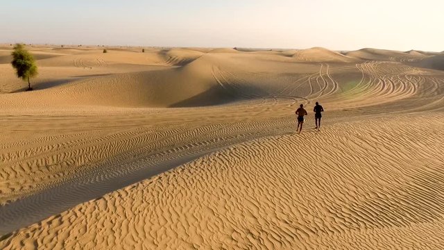 two sportsmen run in the desert. dron arial shots. Duba desert. UAE