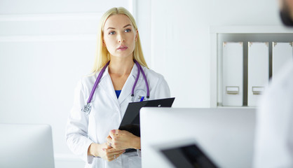 Woman doctor standing with folder at hospital