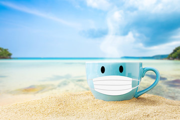 cup of coffee on white sand beach over blue sky and sea on day noon light background