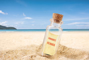 bottle on sand beach with seashell over blurred tropical blue sea and clear blue sky