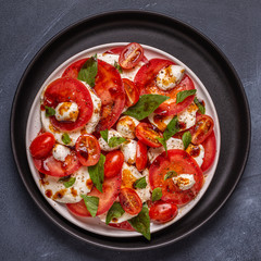 Italian caprese salad with sliced tomatoes, mozzarella cheese, basil, olive oil, balsamic vinegar.
