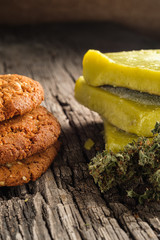 biscuits with marijuana and cannabis butter and bud on an old wooden background close-up. Healthy medical food with cannabis. the buds are inaccurately scattered. rustic. Vertical.