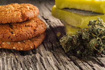 biscuits with marijuana and cannabis butter and bud on an old wooden background close-up. Healthy medical food with cannabis. the buds are inaccurately scattered. rustic. Horizontal.