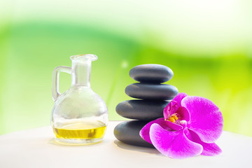 Fototapeta na wymiar Hot fragrance oil aroma therapy massage with stone over blurred green spring garden background for relaxing image concept. 
