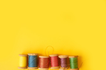 Colored coils with threads on a yellow background. Handicrafts and sewing.
