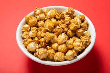 Plate with caramel popcorn on a red background