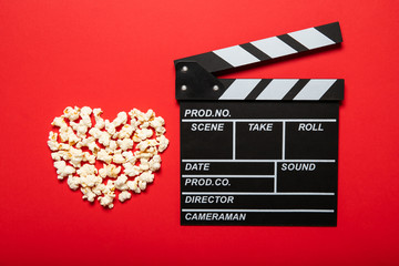 Movie clapper and popcorn on a red background