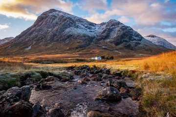Cottage overlooked by Etive Mor, Glencoe in the dramatic highlands of scenic Scotland, fantastic adventure travel destination or holiday vacation to view picturesque scenery at sunrise or sunset © Andy