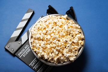 Plate with popcorn and movie clapper board on a blue background