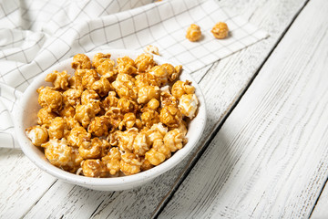 Plate with caramel popcorn on a wooden background. Place for text