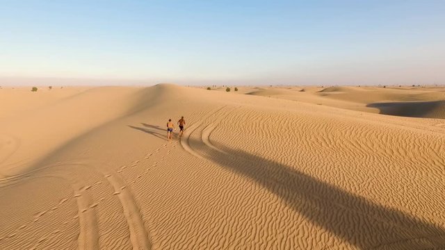 two sportsmen run in the desert. dron arial shots. Duba desert. UAE