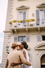 Wedding in Florence, Italy. Multiracial wedding couple. African-American bride in a white dress with a long veil and a bouquet, and Caucasian groom in a sandy jacket and straw hat.