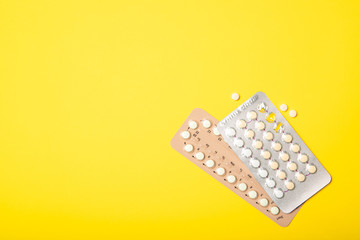 Female oral contraceptive pill blister on a yellow background background.