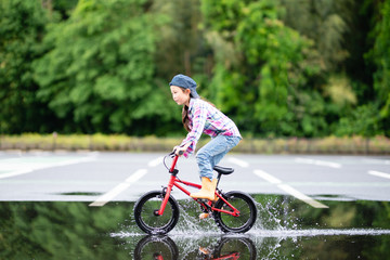 水溜まりで自転車に乗る女の子