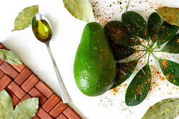 avocado, avocado oil, seasoning, green leaves. All ingredients for a salad of eternal youth. On white background