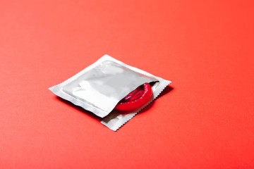 Colored condom on a red background. Medicine and healthcare