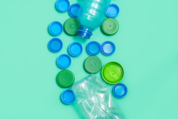 Composition of plastic bottles and plastic bottle caps on green background with space for text