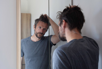 Man looking anxious in bathroom mirror