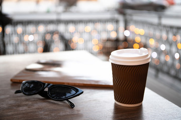 Paper cup with coffee and a magazine on a table in a cafe