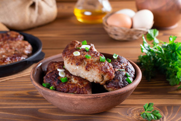 Homemade roasted beef cutlets in a ceramic bowl on wooden table