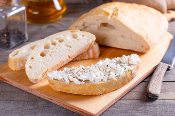 Freshly baked sliced bread on wood cutting board with cottage cheese