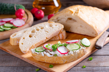 sandwiches with cucumbers, radishes and cream cheese on wooden board, Breakfast or lunch concept