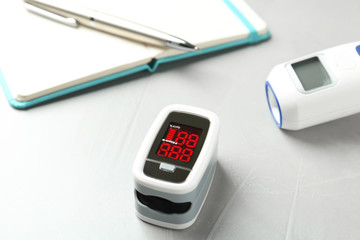 Modern fingertip pulse oximeter on light grey stone table, closeup