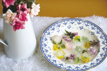 Beauty and skin care concept. Flowers and ice cubes in fresh water for beauty routine