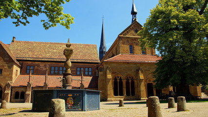 Frontseite und Vorhalle der Klosterkirche von Maulbronn und Klosterbrunnen unter blauem Himmel