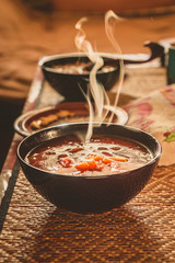 Steam over hot soup in a black plate in the village