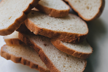 Scattered pieces of white dried bread lie on a white background. Photography, concept.