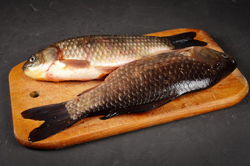 two fresh crucian carp lie on a cutting board, vignetting