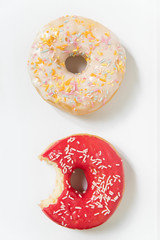 Donut day. Bitten colored donuts with colorful sprinkles on white background. Copy space, close-up