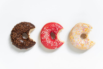 Donut day. Bitten colored donuts with colorful sprinkles on white background. Copy space, close-up