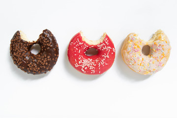 Donut day. Bitten colored donuts with colorful sprinkles on white background. Copy space, close-up
