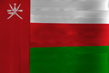 Colorful ribbon as Oman national flag, white red and green with a vertical red stripe, charged with the National emblem.