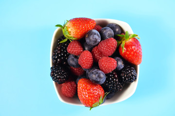 White plate with berries on a blue background
