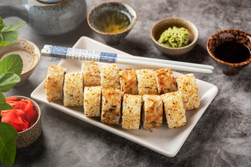 a portion sushi rolls on a plate on the table, close-up