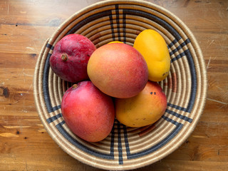 Mangoes in Woven Bowl on Wood Background